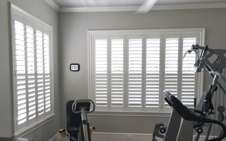 Draft-blocking window treatments are especially important in spaces with windows on more than one wall. Honolulu exercise room with shuttered windows.